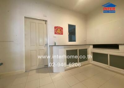 Moderately lit kitchen interior with tiled flooring and storage cabinets
