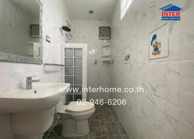 Bathroom with white tiled walls, toilet, and sink