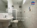 Bathroom with white tiled walls, toilet, and sink