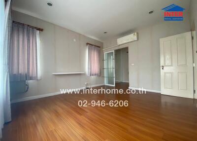 Spacious empty bedroom with wooden flooring and air conditioner