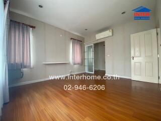 Spacious empty bedroom with wooden flooring and air conditioner