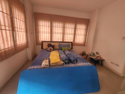 Bedroom with a double bed, bedside table, and large windows with blinds