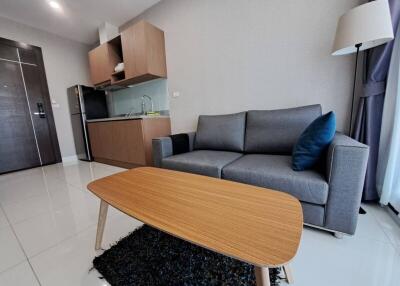 Modern living area with sofa, coffee table, and kitchenette