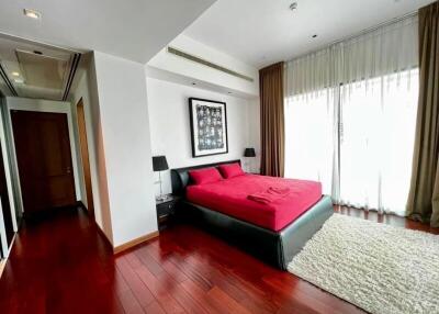 Spacious bedroom with red bedding and large windows