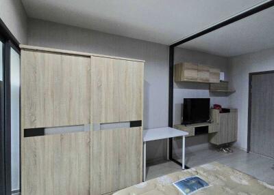 Modern bedroom with wooden wardrobe, wall-mounted TV, and work desk