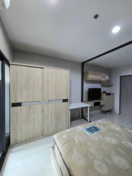 Modern bedroom with wooden wardrobe, wall-mounted TV, and work desk