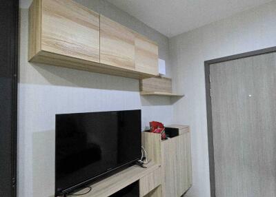 Modern living area with wooden shelves, TV, and storage unit