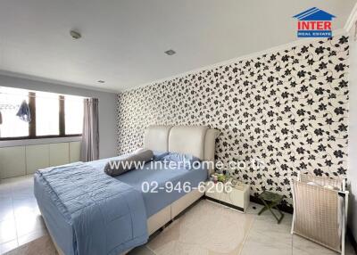 Spacious bedroom with a large bed, wall decor, and ample natural light