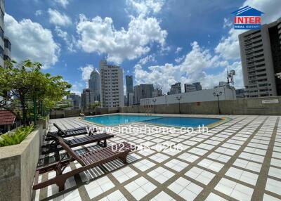 Outdoor swimming pool area with a clear blue sky and cityscape view