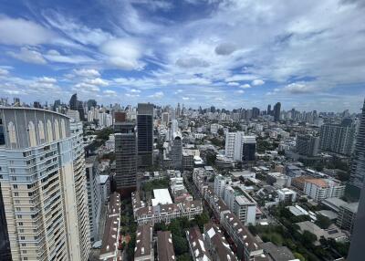 Panoramic view of a city with numerous high-rise buildings under a partly cloudy sky