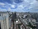 Panoramic view of a city with numerous high-rise buildings under a partly cloudy sky