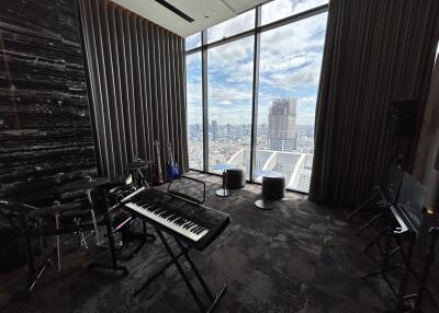 Spacious room with a musical setup and a large window with a city view