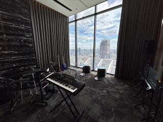 Spacious room with a musical setup and a large window with a city view