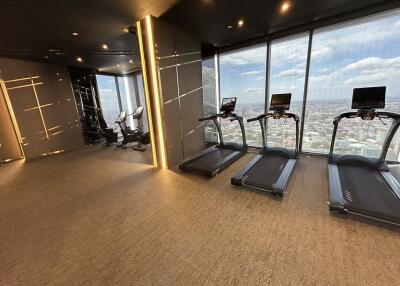 Modern gym with treadmills and exercise bikes, with a city view.