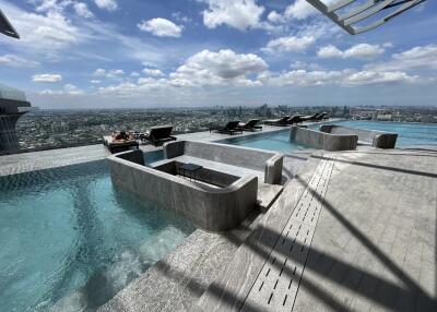 Infinity pool area with lounge chairs and city skyline view