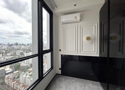 A small room with large windows providing a city view, modern wall panels, and an air conditioning unit.
