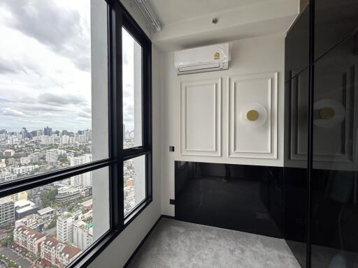 A small room with large windows providing a city view, modern wall panels, and an air conditioning unit.