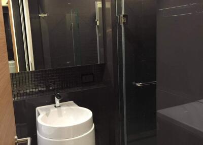 Modern bathroom with dark tiles and a glass shower door