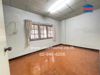 Empty bedroom with wood flooring, curtains, and fluorescent light