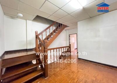 Staircase area with polished wooden floors and railing, doorway in the background