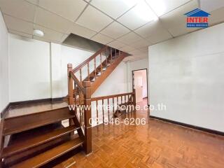 Staircase area with polished wooden floors and railing, doorway in the background