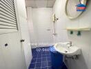 Simple bathroom with blue floor tiles and white wall tiles.