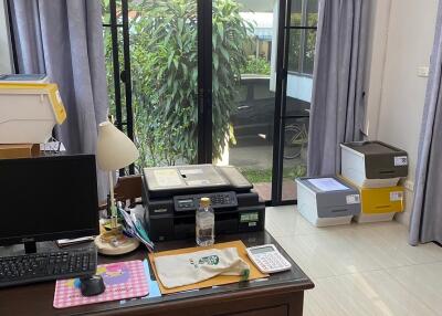 Home office with desk, computer, and printer next to large window capturing natural light