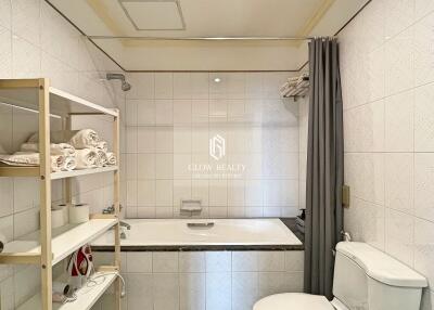 Clean and well-lit bathroom with bathtub and shelving