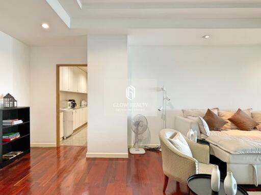 Modern living room featuring hardwood floors with an adjacent view of a kitchen