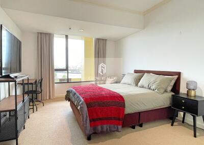 spacious bedroom with large window, double bed, desk, and nightstand