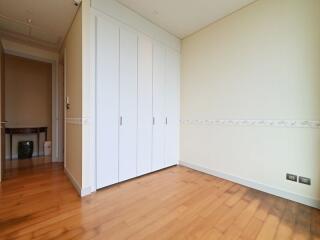 Spacious bedroom with wooden flooring and a large built-in wardrobe