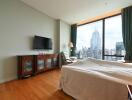 Bedroom with a large window offering city views and a mounted flat-screen TV