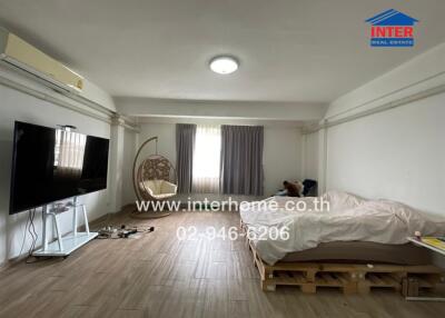 Bedroom with wooden floor, bed, and television