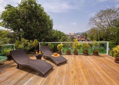Spacious terrace with lounge chairs and a view of surrounding greenery