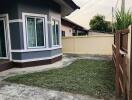 View of the side yard with freshly cut grass and a border of a house with large windows