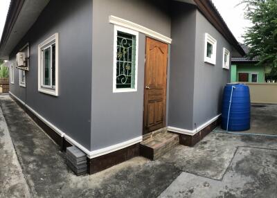 Exterior view of a grey house with a wooden door and windows