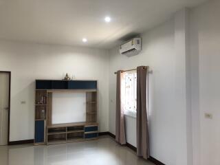 Modern living room with light-colored walls, a storage unit, and an air conditioner