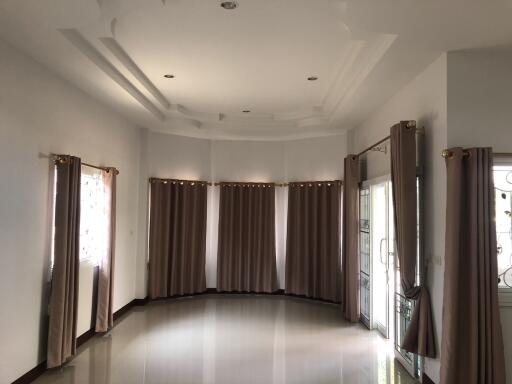 Spacious living room with large windows and curtain-covered sliding doors