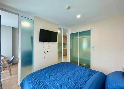 Modern bedroom with blue bedding and mounted TV