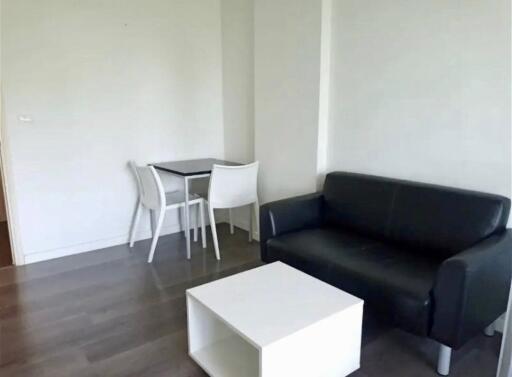 Living area with black leather sofa, white coffee table, and dining set