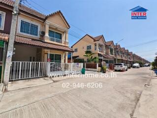 Exterior view of a row of townhouses with a driveway and gated front entrances