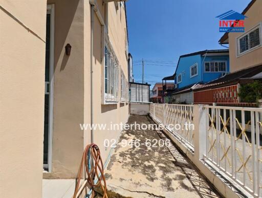 Outdoor walkway area beside house with fencing and neighboring houses in the background