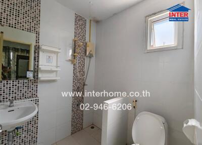 Small white-tiled bathroom with a shower, sink, and toilet