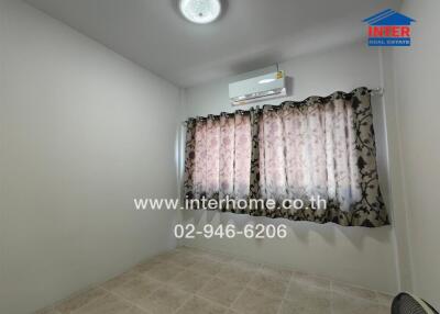 A small bedroom with tiled floor, window with patterned curtains, air conditioner, and ceiling light.