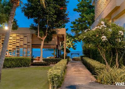 Pathway leading to modern outdoor seating area with greenery and ocean view