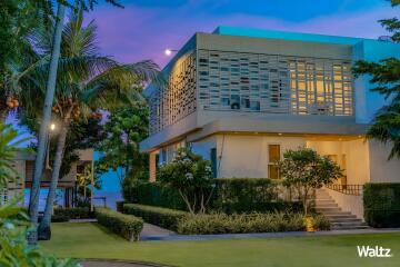 Modern two-story house with landscaped yard and evening lighting