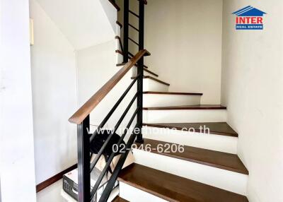 Inner staircase with wooden steps and black railing