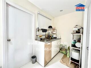 Small kitchen with sink, storage shelves, and various kitchen items