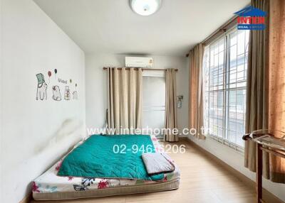 Simple bedroom with a mattress on the floor and large window with curtains