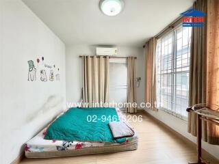 Simple bedroom with a mattress on the floor and large window with curtains